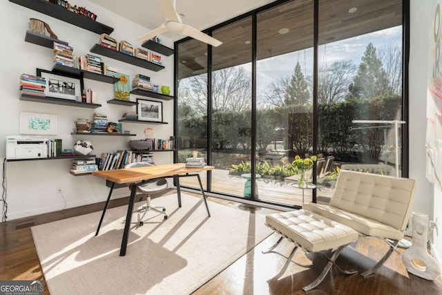 home office with baseboards, plenty of natural light, floor to ceiling windows, and wood finished floors