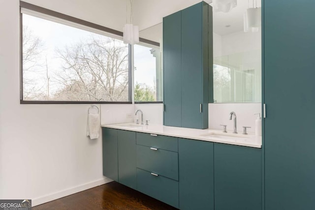 bathroom with wood finished floors, a sink, baseboards, and double vanity