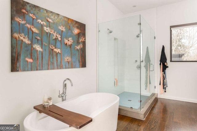 full bathroom featuring a stall shower, a freestanding tub, and wood finished floors