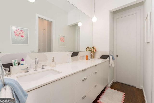 bathroom featuring double vanity, wood finished floors, and a sink