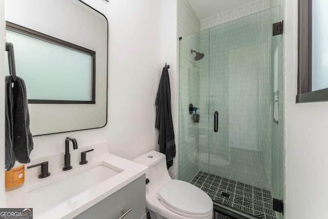 bathroom featuring vanity, a shower stall, and toilet