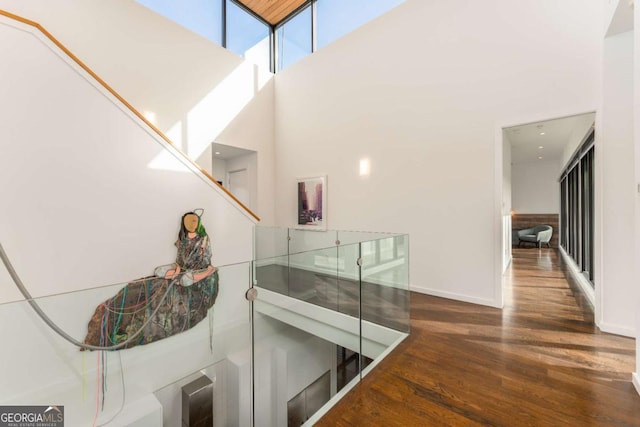 hall with baseboards, a high ceiling, and wood finished floors