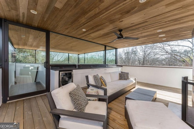 wooden deck with beverage cooler, a sink, and an outdoor living space