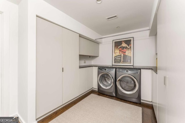 laundry area featuring dark wood-type flooring, independent washer and dryer, and visible vents