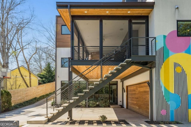 view of exterior entry featuring a garage, fence, and stucco siding