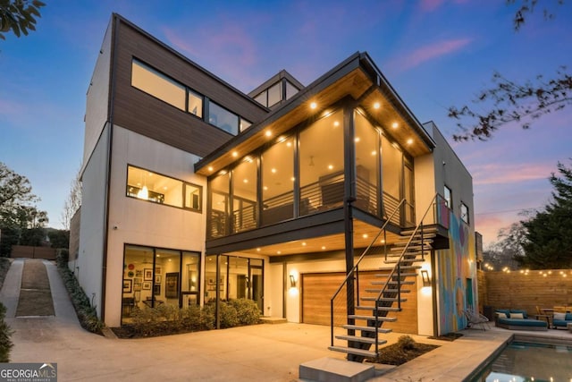 rear view of house featuring a garage, stairs, driveway, a fenced in pool, and a patio area