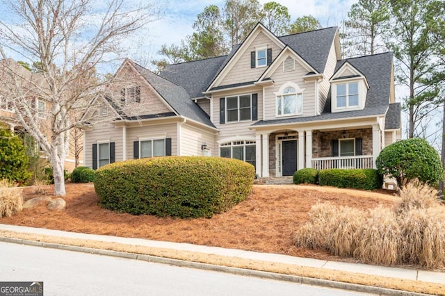 craftsman house featuring stone siding, a porch, and roof with shingles