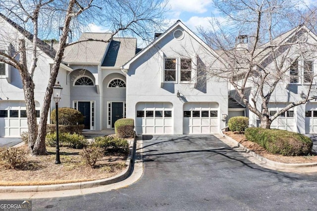 view of front facade with driveway, a garage, a chimney, and stucco siding