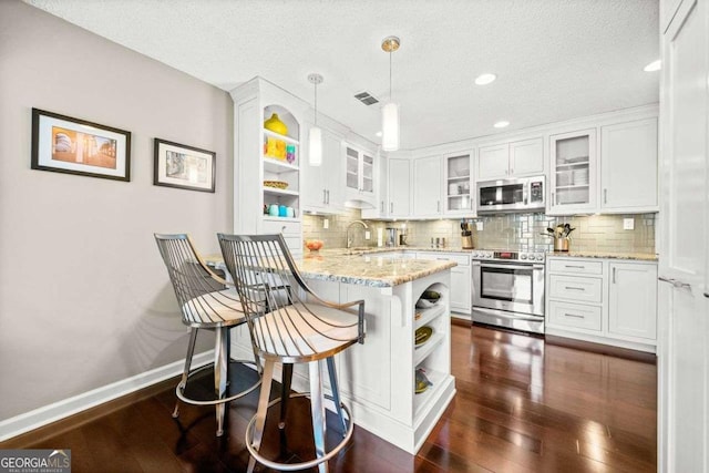 kitchen featuring dark wood-style flooring, a peninsula, stainless steel appliances, white cabinetry, and open shelves