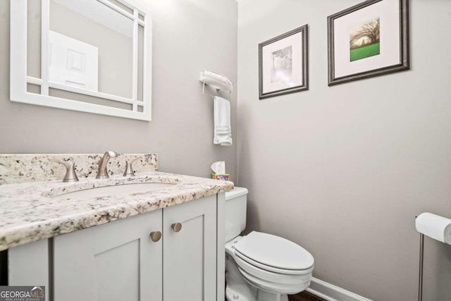 bathroom featuring vanity, toilet, and baseboards