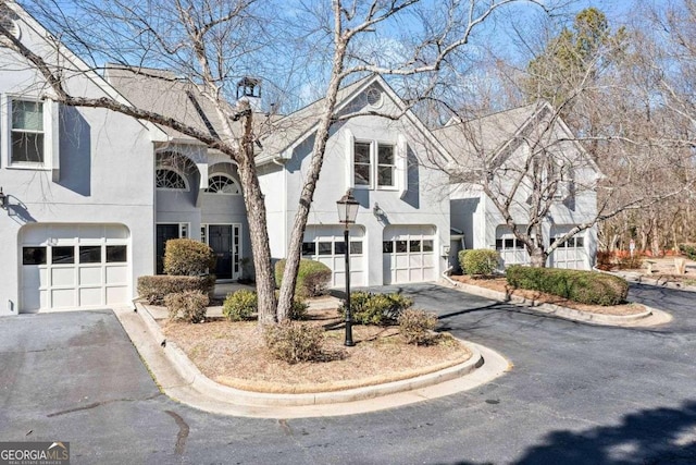 view of front of house with a garage, driveway, and stucco siding