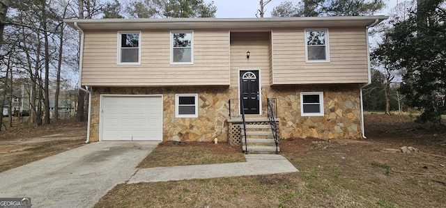 bi-level home featuring stone siding, an attached garage, and driveway