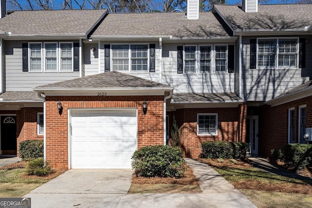 townhome / multi-family property with a garage, brick siding, a shingled roof, and a chimney