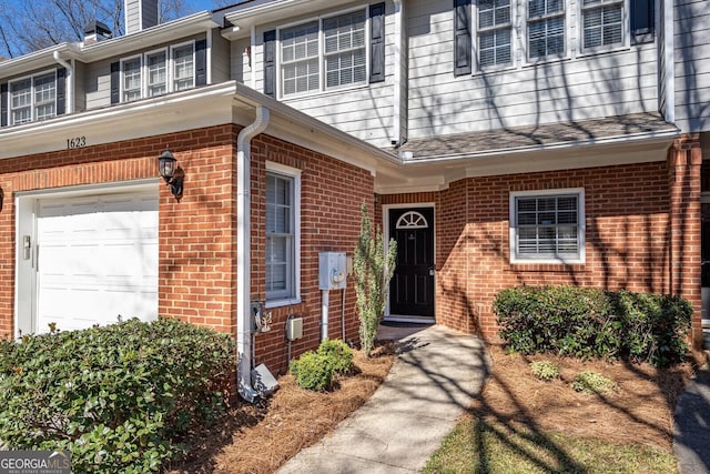 property entrance with brick siding and an attached garage