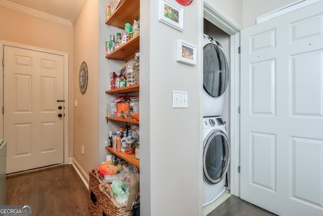 clothes washing area featuring stacked washer and clothes dryer, ornamental molding, dark wood-type flooring, laundry area, and baseboards