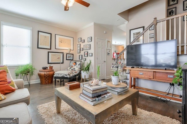 living area featuring crown molding, stairway, a ceiling fan, wood finished floors, and baseboards