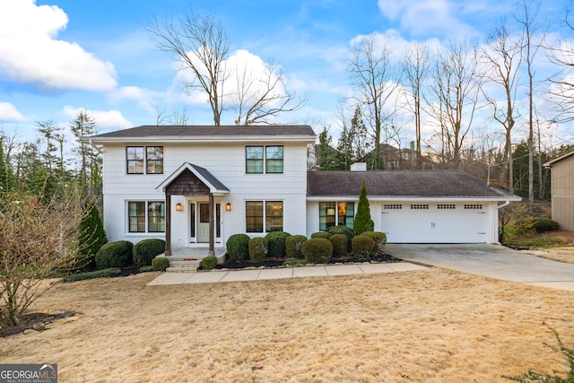 colonial inspired home featuring concrete driveway, an attached garage, and brick siding