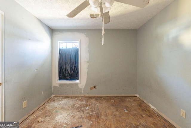 empty room featuring a ceiling fan, visible vents, a textured ceiling, and baseboards