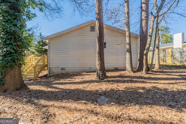 view of side of home featuring crawl space and fence