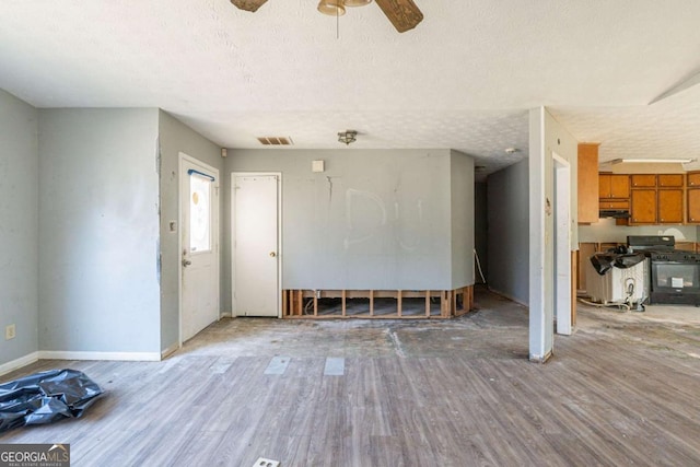 unfurnished living room with visible vents, a ceiling fan, a textured ceiling, light wood-type flooring, and baseboards