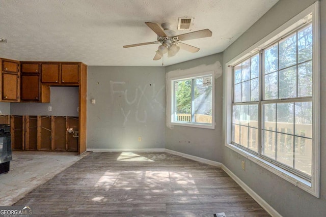 interior space with light wood-style floors, visible vents, baseboards, and a textured ceiling