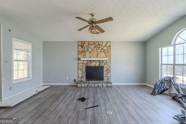 unfurnished living room with a textured ceiling, wood finished floors, plenty of natural light, and a fireplace