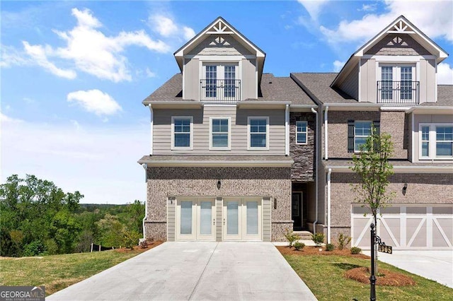 view of front of house featuring driveway, brick siding, an attached garage, and french doors