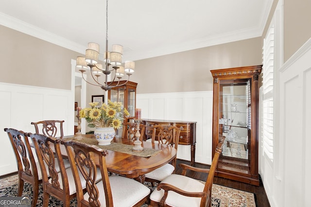 dining space with ornamental molding, wainscoting, an inviting chandelier, and wood finished floors