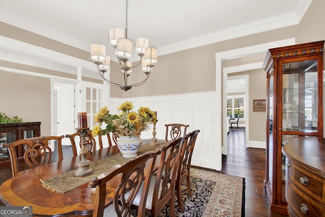 dining room with a notable chandelier, ornamental molding, a decorative wall, and wood finished floors