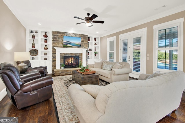 living room with dark wood-type flooring, a fireplace, crown molding, and built in shelves