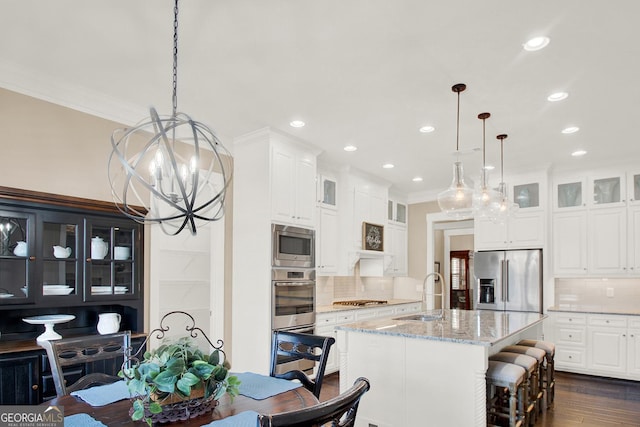 kitchen with light stone counters, stainless steel appliances, dark wood-style flooring, a sink, and ornamental molding