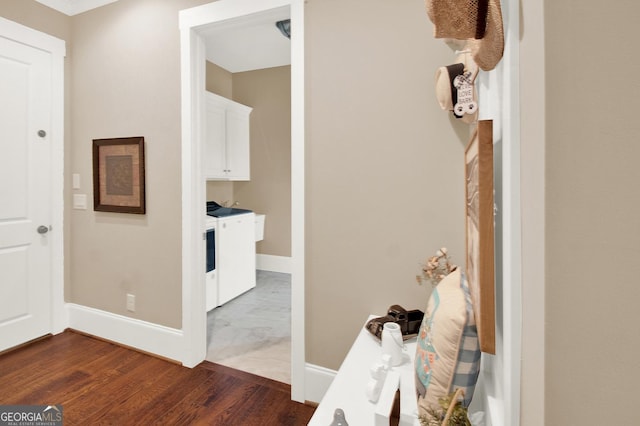 hallway with baseboards, washer and clothes dryer, and dark wood-style flooring