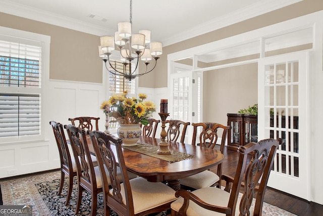 dining room with ornamental molding, visible vents, a decorative wall, and a chandelier