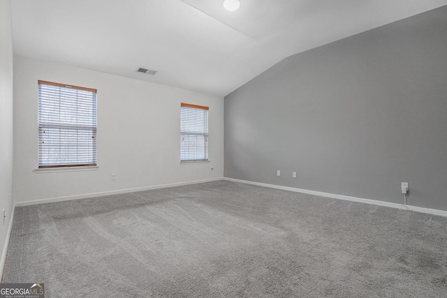 unfurnished room featuring lofted ceiling, carpet floors, plenty of natural light, and visible vents