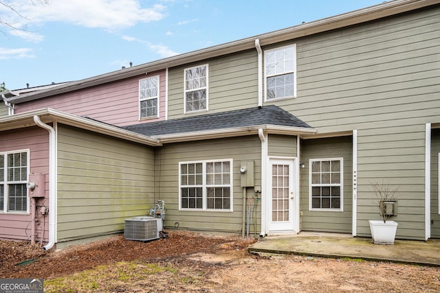 back of house featuring a shingled roof and central AC unit