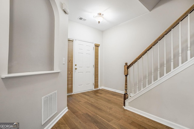 foyer featuring stairs, visible vents, baseboards, and wood finished floors