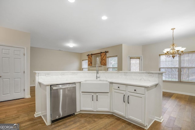 kitchen featuring a kitchen island with sink, wood finished floors, a sink, white cabinets, and dishwasher