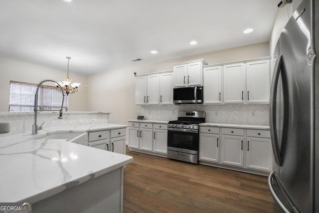 kitchen featuring decorative backsplash, dark wood-style flooring, stainless steel appliances, white cabinetry, and a sink