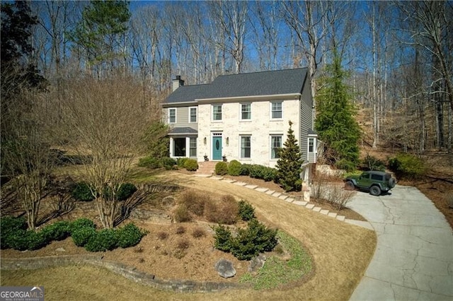 colonial inspired home featuring driveway and a chimney