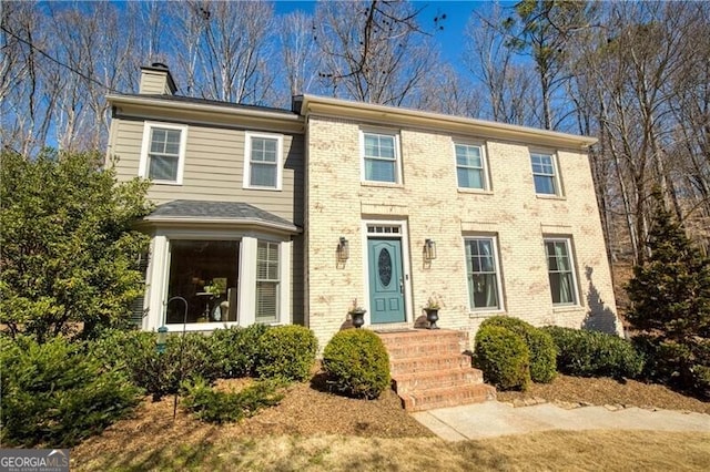 view of front of house with brick siding and a chimney