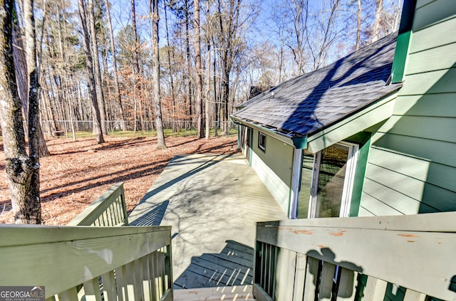 view of side of home featuring fence and roof with shingles