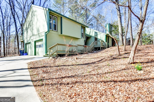 view of property exterior featuring driveway, an attached garage, and a chimney