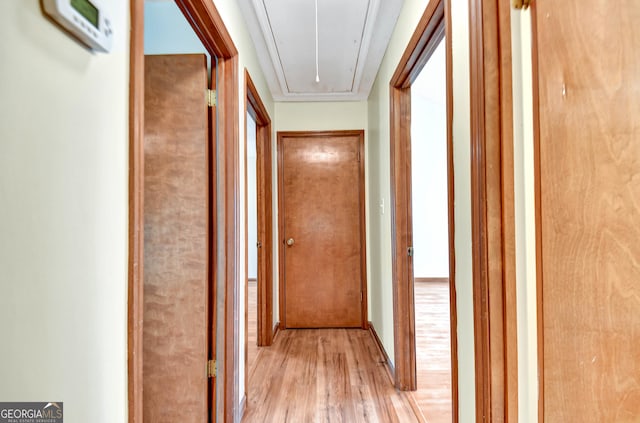 hall with light wood-style floors and attic access