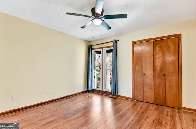 unfurnished bedroom featuring visible vents, baseboards, a textured ceiling, light wood-type flooring, and a closet