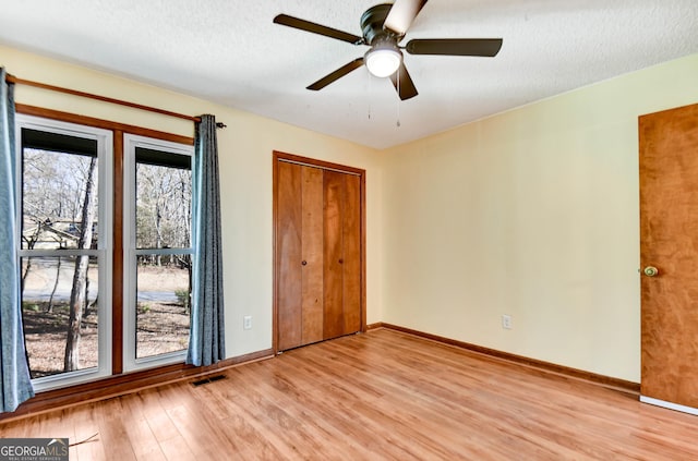 unfurnished bedroom with baseboards, visible vents, ceiling fan, a textured ceiling, and light wood-style floors