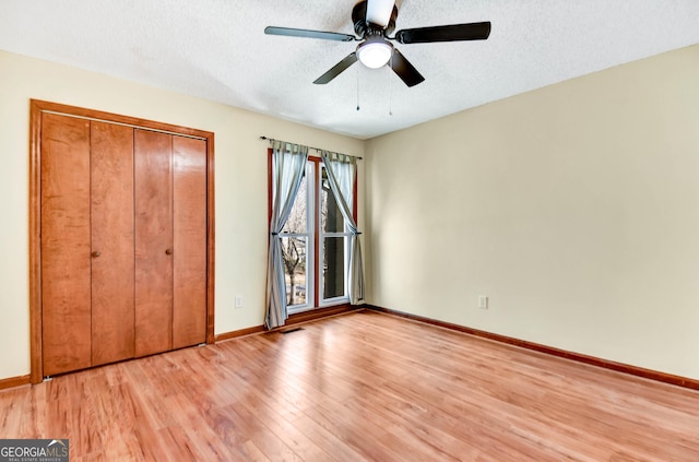 unfurnished bedroom with light wood finished floors, baseboards, a ceiling fan, a textured ceiling, and a closet