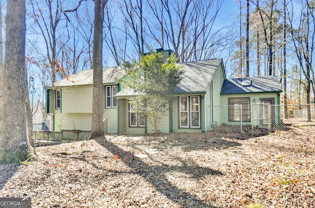 view of front of property with a shingled roof, a chimney, and fence