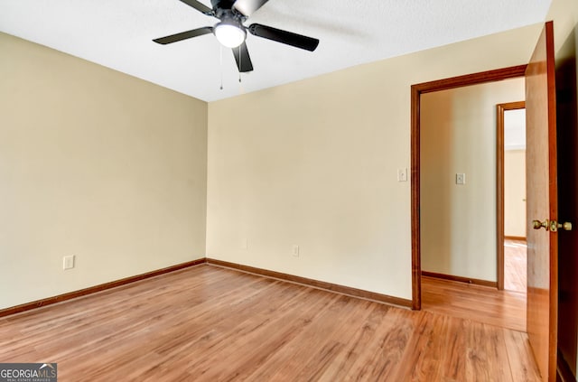 empty room with light wood-type flooring, a ceiling fan, and baseboards