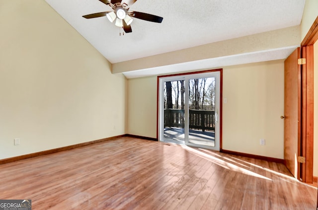 spare room with baseboards, a ceiling fan, wood finished floors, vaulted ceiling, and a textured ceiling