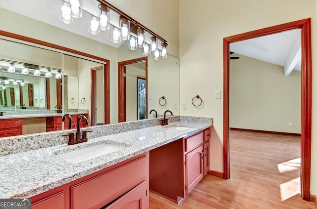 full bathroom with double vanity, baseboards, a sink, and wood finished floors